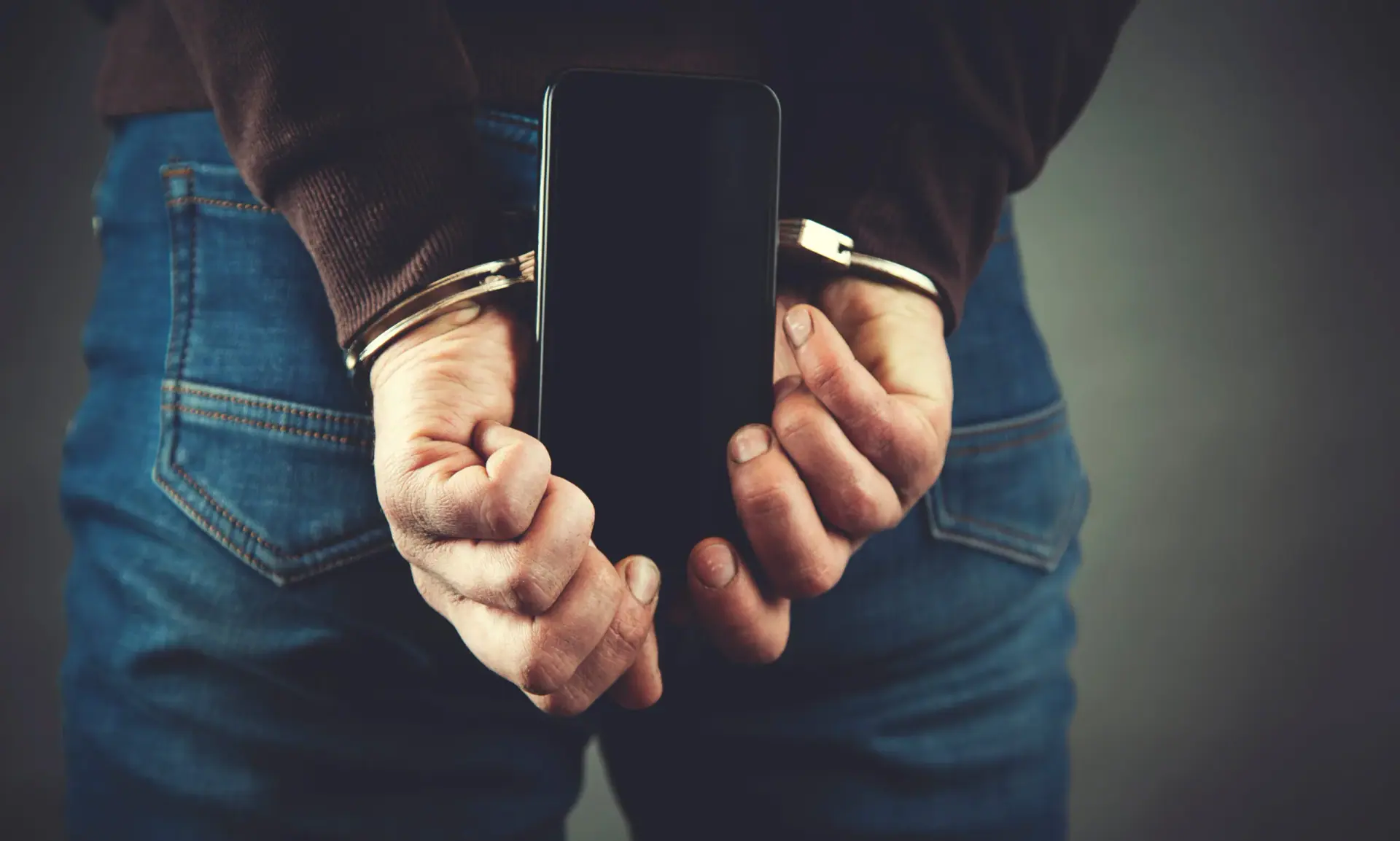 young business man hand handcuffs and phone